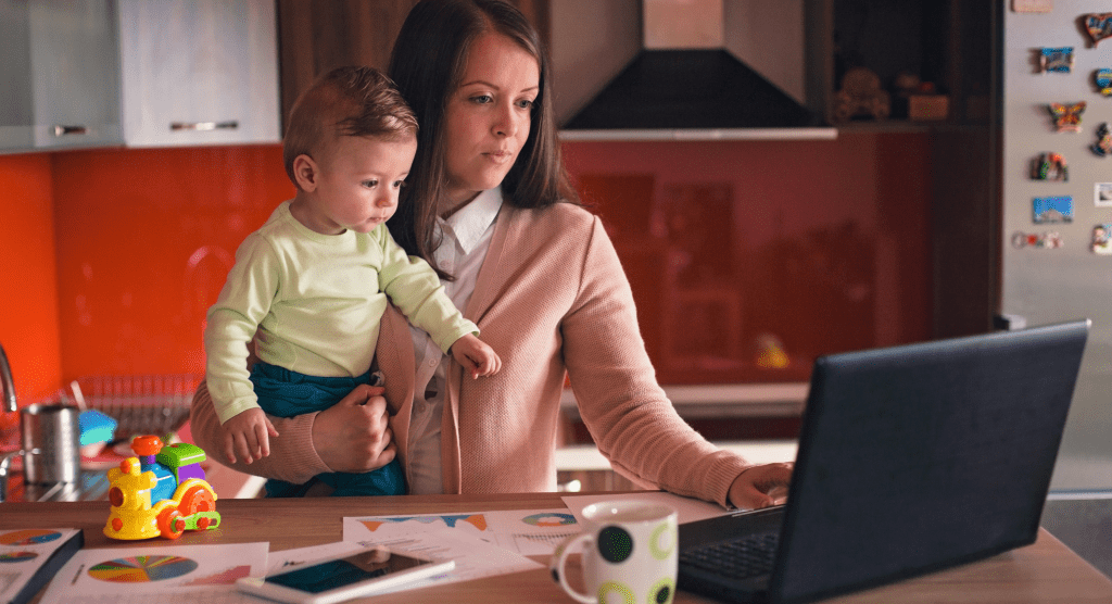 mom working on laptop holding toddler